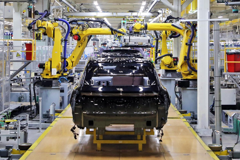 2023年12月10日，江蘇常州一汽車基地的生產(chǎn)車間，機(jī)器臂在組裝新能源汽車。