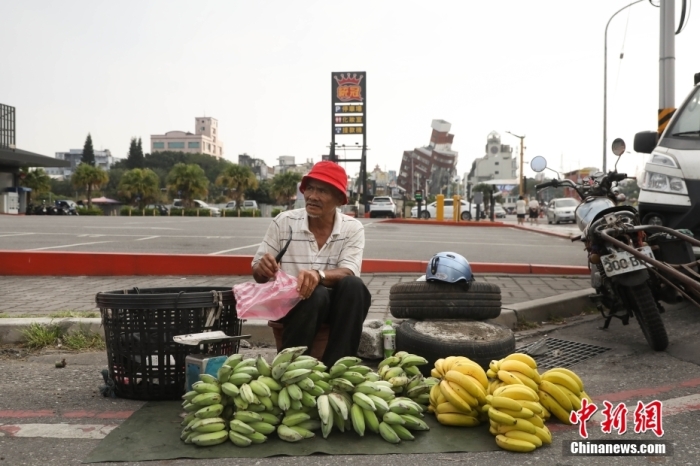 資料圖：臺(tái)灣花蓮市區(qū)博愛(ài)路早市，商販在街頭擺攤售賣(mài)水果，不遠(yuǎn)處是因震傾斜嚴(yán)重的天王星大樓。 中新社記者 楊程晨 攝.jpg
