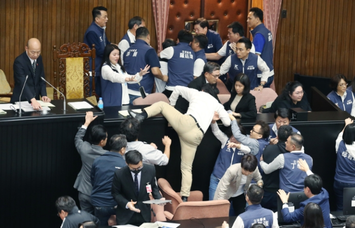 民進(jìn)黨立委郭國文（中背影者）卻翻上桌，遭國民黨立委攔阻