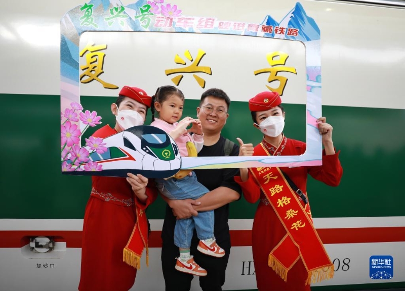 2023年7月1日，乘客與乘務(wù)人員在西寧至格爾木動(dòng)車組首發(fā)列車前合影留念。（圖源：新華社）